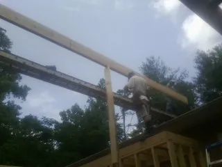 Carpenter setting a ridge beam over a new addition frame — Ice Dam Removal by Roofing Brothers in Buck Creek
