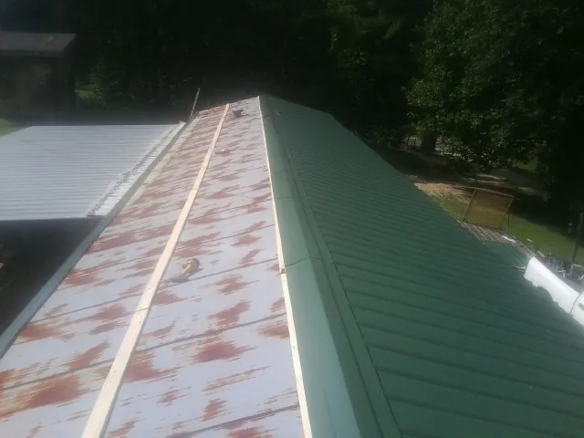 Old rusted panels beside newly installed green metal roofing — Wind Damage Roof Repair by Roofing Brothers in Buck Creek