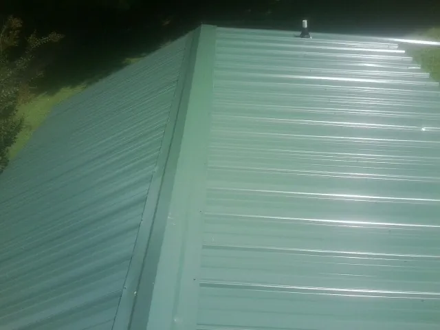 New green metal panels meeting at the ridge of a roof — Flat Roof Repair work by our crew in Buck Creek