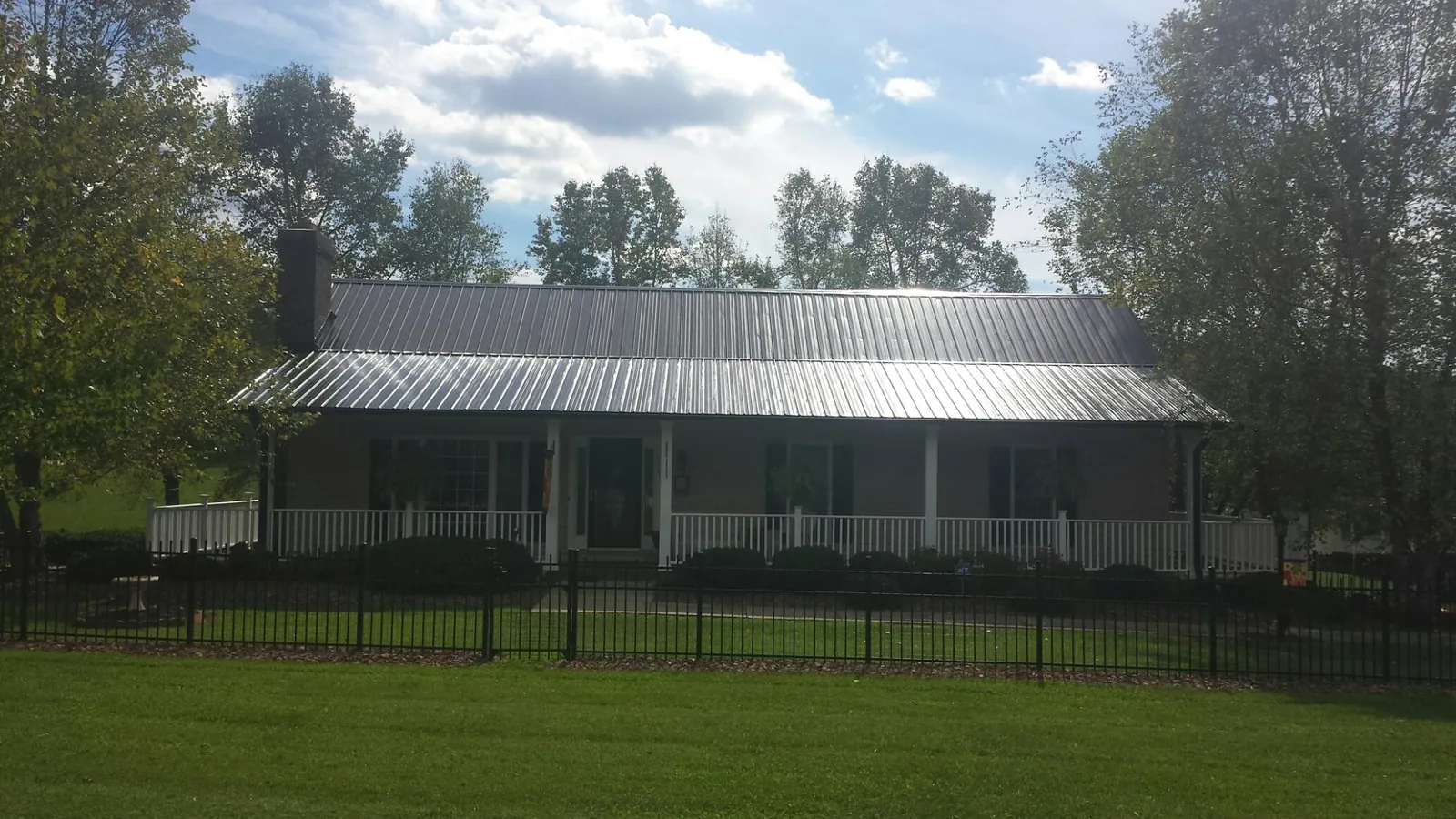 Gray metal roof on a brick ranch with a full width front porch — Gutter Guard Installation work by our crew in Buck Creek
