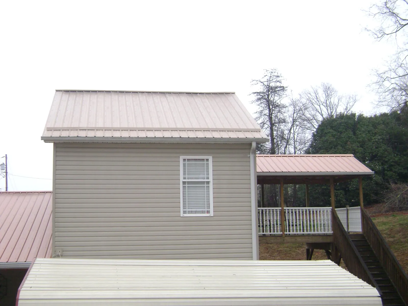 Tan metal roofs on a two story addition and attached porch, from a Roof Replacement job in Buck Creek
