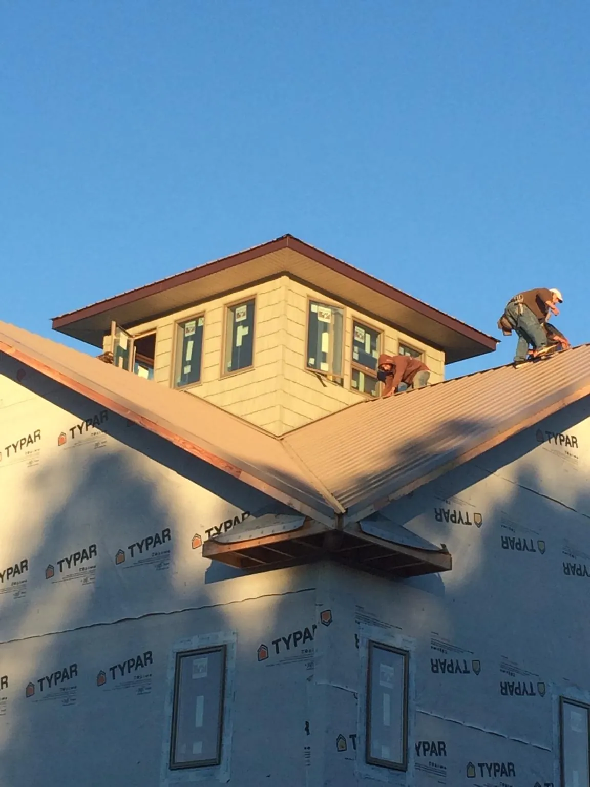 Roofers working around a rooftop cupola on a new metal roof at sunset — Roof Waterproofing in Buck Creek by Roofing Brothers